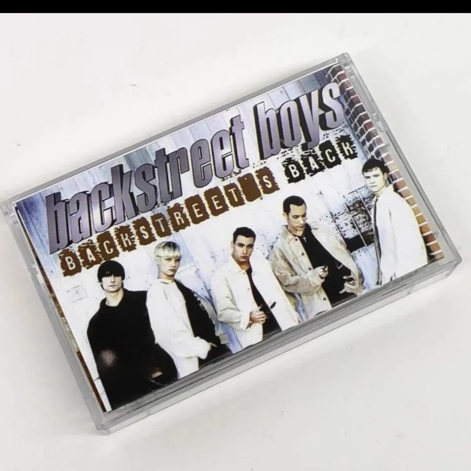 Audio Music For - เทปคาสเซ็ตเสียงเพลงป๊อปอะนาล็อกวินเทจ กลุ่มบอยแบนด์ฮาร์โมนี แทร็กเพลงย้อนยุค ปกภาพบุคคลบนกำแพงอิฐ ดนตรีกายภาพที่ชวนให้คิดถึงอดีต